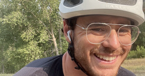 Daniel on a road ride, wearing a cycling helmet and sunglasses